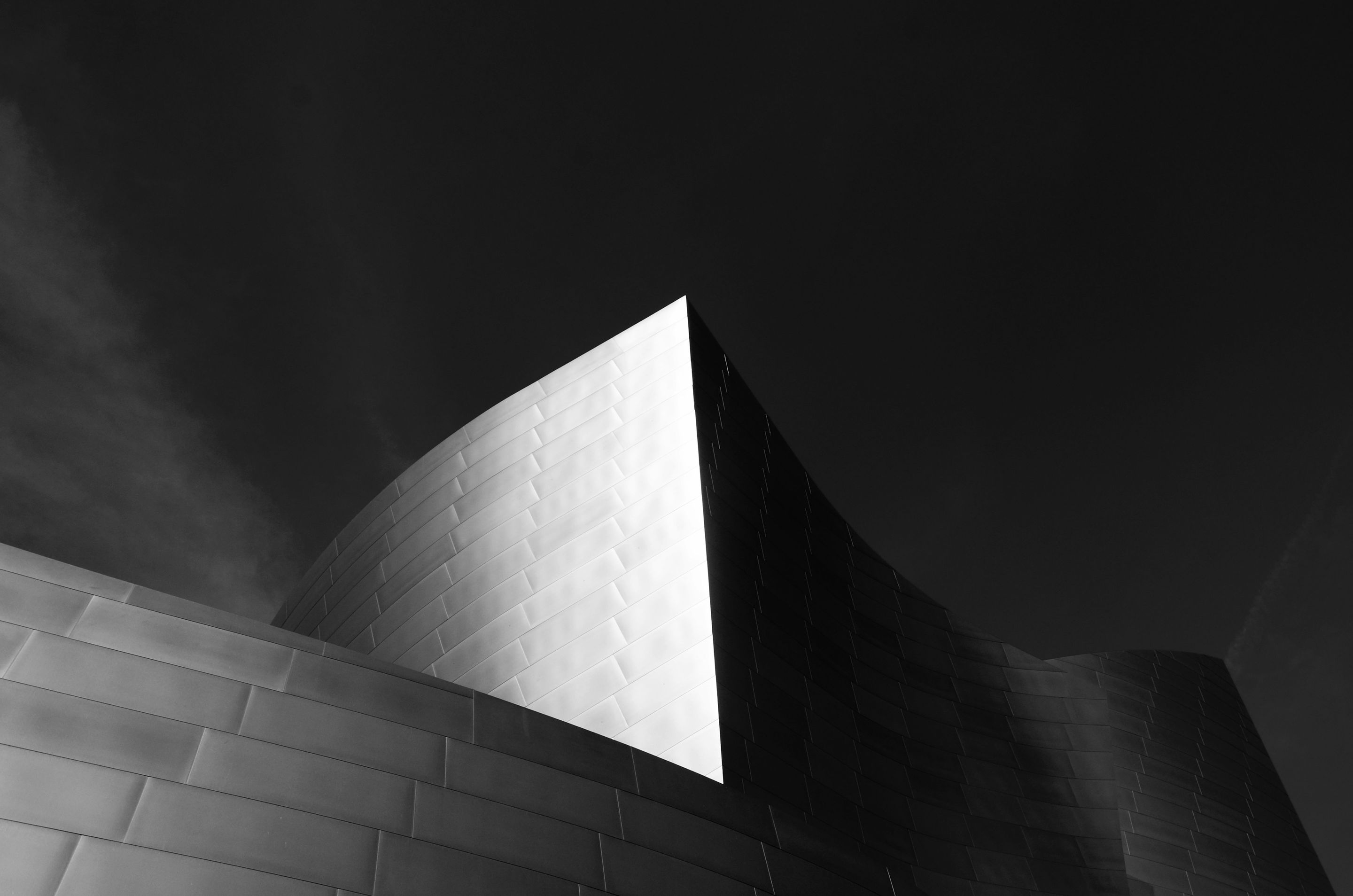 Geschwungene Fassade aus Stahl vor dunklem Himmel, Walt Disney Concert Hall